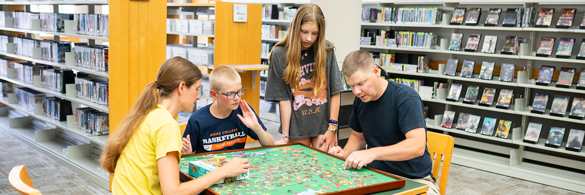 Family putting a puzzle together in the library