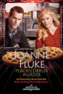 "Peach Cobbler Murder" book cover with a man and woman with a kitchen in the background.  The couple are peering into an open oven with two pies.  The audience is from the perspective of the inside of the oven. 