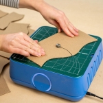 Hands pushing cardboard through ChompSaw machine